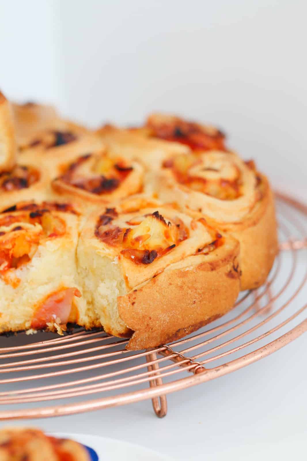 Soft homemade savoury scrolls on a copper wire rack.